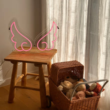 Load image into Gallery viewer, clear-acrylic-angel-wing-shape-neon-table-light-in-a-playroom-next-to-a-pram-filled-with-dolls
